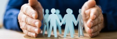 A person's hands holding a paper cutout of a group of people holding hands.