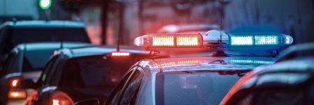 A police siren on top of a police car standing in a line of cars.