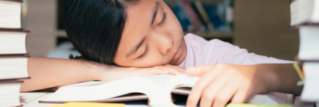 A young girl is asleep on her book.
