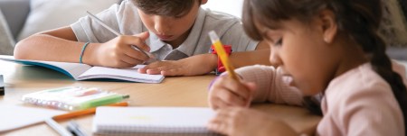 Two young students writing in their notebooks.