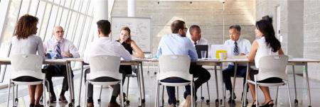 A team of people sitting at a long table in a modern office space.