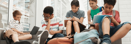 A group of kids are sitting on the floor and writing in their notebooks.