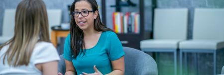 A practitioner explains something to a client who is sitting across from them. They look passionate about what they are sharing with their client.