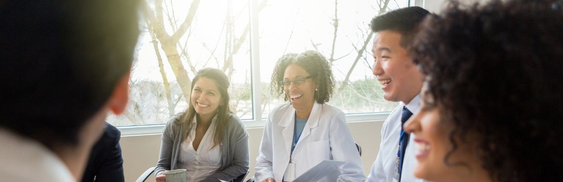 A group of health professionals sitting next to each other and smiling.