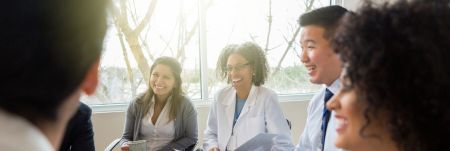 A group of health professionals sitting next to each other and smiling.