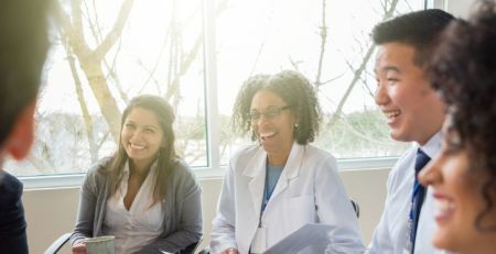 A group of health professionals sitting next to each other and smiling.