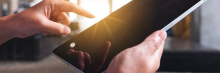 Hands holding an iPad and pointing to the screen.