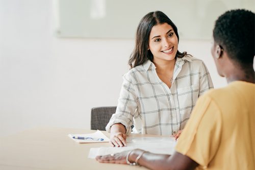 Two people sit across from each other at a table, having an engaging conversation in a casual setting.