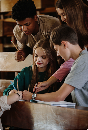 CBRS-Purpose_8f69d1 Students collaborating in a classroom at wooden desks
